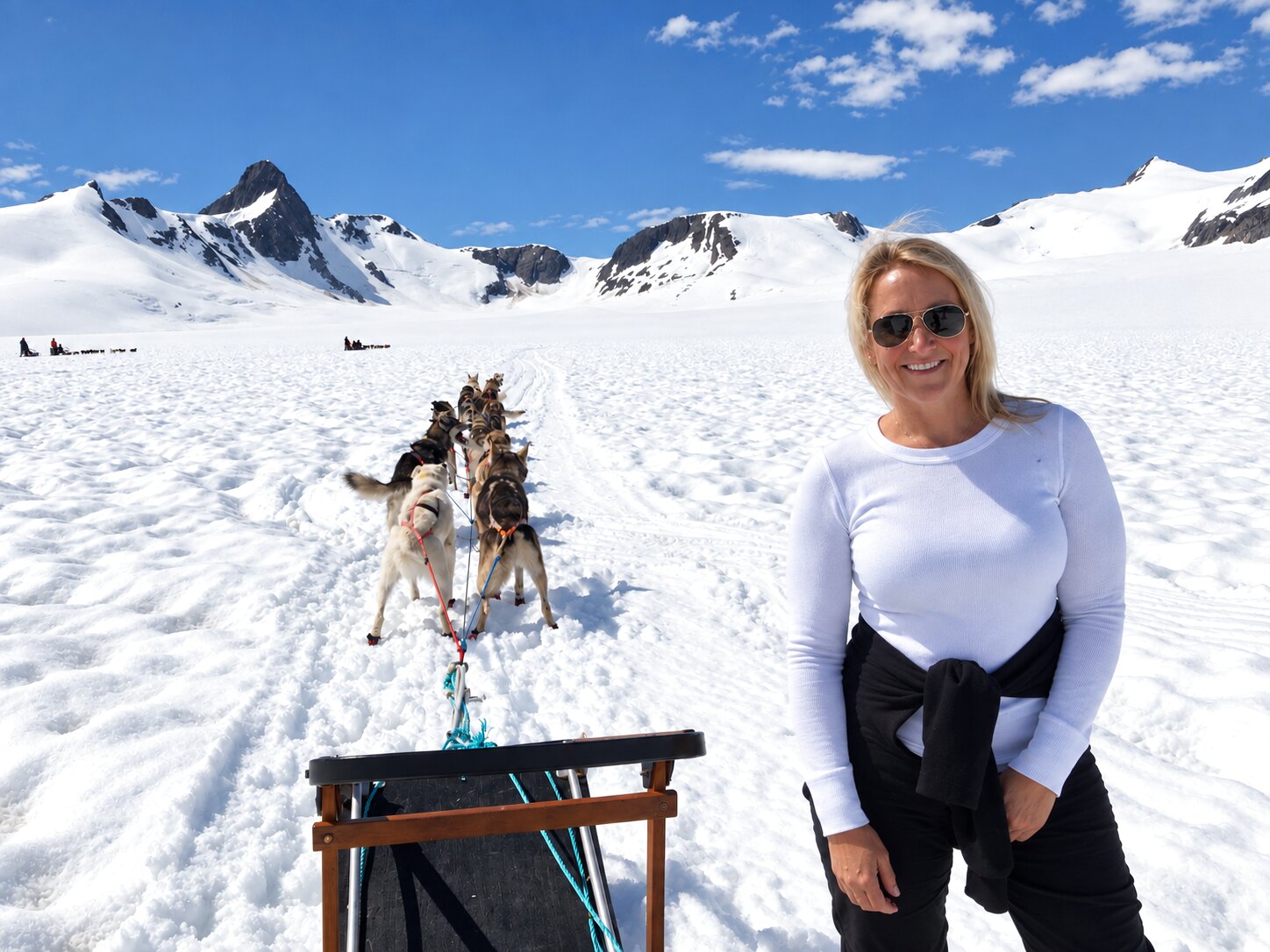 Megan beside a dog sled on a snowy glacier in Alaska