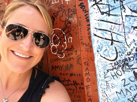 Megan beside a colorful wall covered with handwritten messages in Cuba