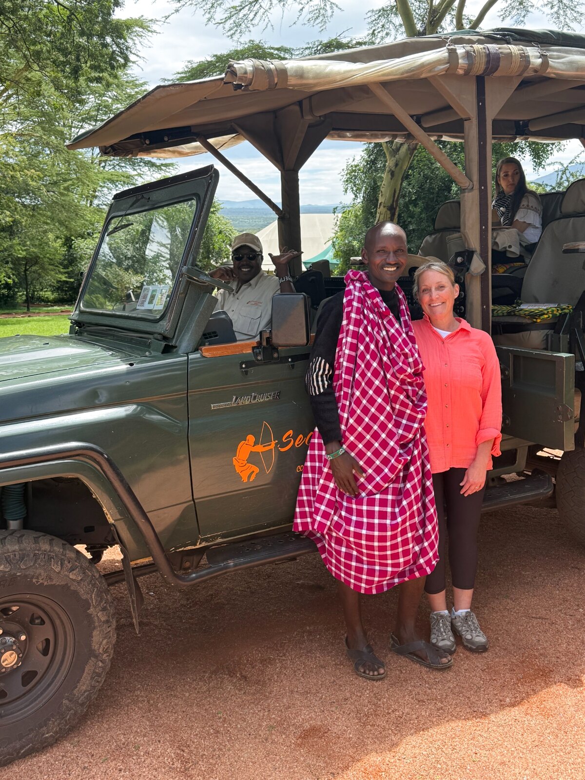Megan with a local guide beside a safari vehicle in Kenya