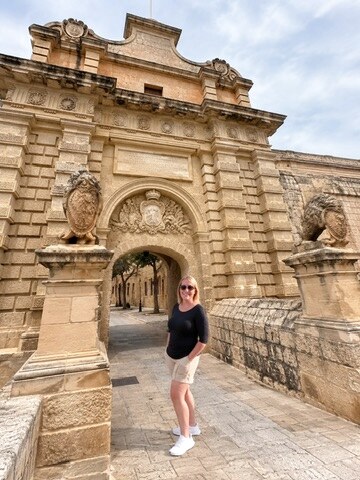 Megan standing beneath the historic gate of Mdina in Malta